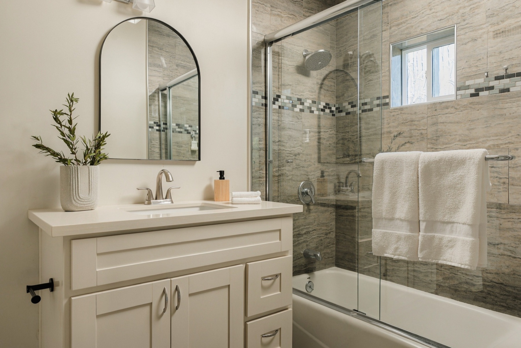 Bathroom with an arched mirror and tiled shower