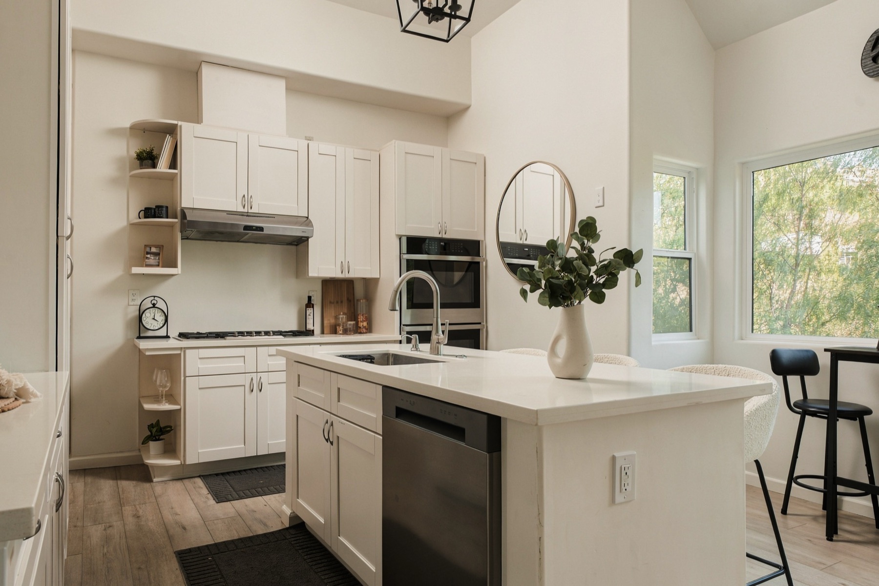 White kitchen with an island, stainless appliances, and a window into the trees